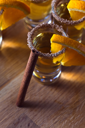 tequila with orange and cinnamon on a wooden tableの写真素材