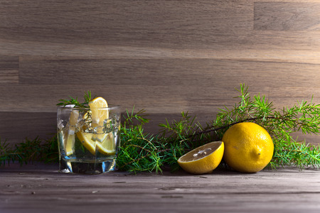 alcoholic drink with lemon and ice on a old wooden tableの写真素材