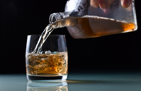 glass with whiskey and ice on a glass tableの写真素材