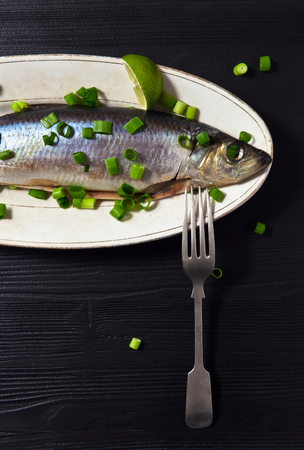 herring with green onion on a black wooden tableの写真素材