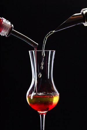 bottle and glass with alcoholic drink on black backgroundの写真素材