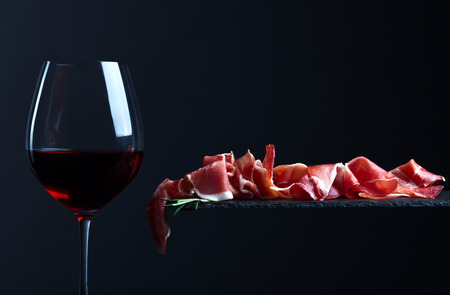 jamon with red wine on a black backgroundの写真素材