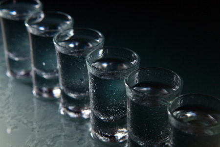 Glasses with  alcoholic drink on a damp glass tableの写真素材