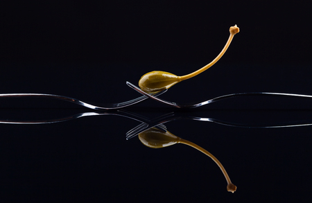 canned capers on a black reflective backgroundの写真素材