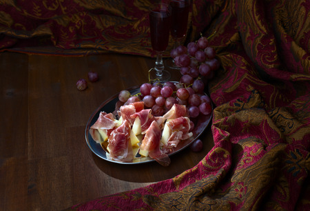 Spanish jamon with melon and grape on wooden tableの写真素材