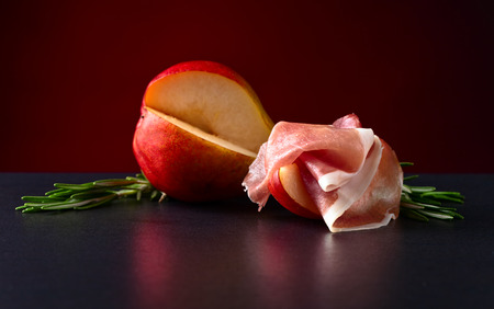 Spanish jamon with pear and rosemary on black tableの写真素材