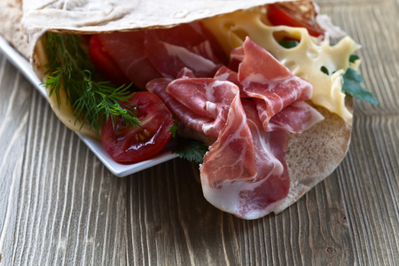 jamon with cheese, tomatoes and greens on  wooden tableの写真素材
