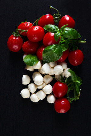 mozzarella with basil and tomatoes on black tableの写真素材