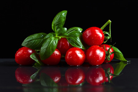 tomatoes with green basil on black tableの写真素材