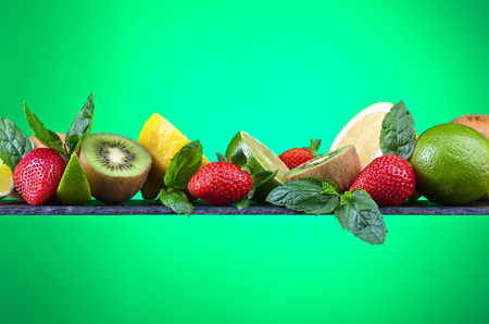 The ripe juicy fruits and peppermint leaves  on green backgroundの写真素材