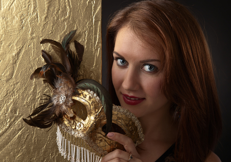 Portrait of young beautiful woman with golden carnival mask