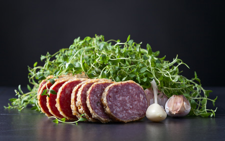 sliced salami with thyme and garlic on a dark backgroundの写真素材