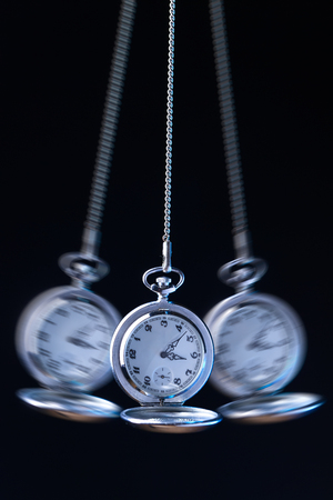 Pocket watch swinging on a chain to hypnotise , black backgroundの写真素材