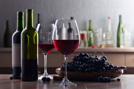 Glass of red wine and grape on a kitchen tableの写真素材