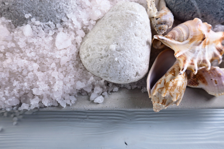 Sea salt on wooden table with stones and shellsの写真素材
