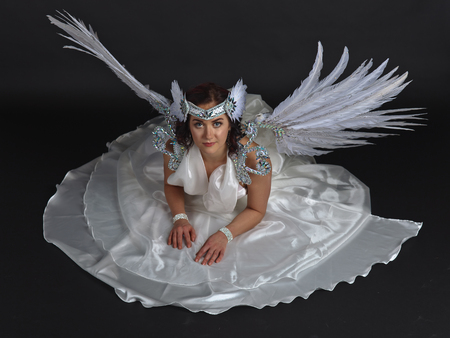 Young beautiful woman in white dress with angel wings on black backgroundの写真素材