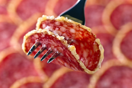 Salami slice on a fork , focus on a foregroundの写真素材