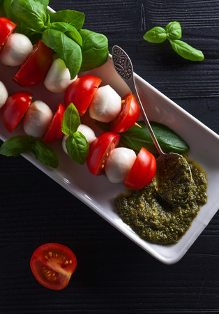  mozzarella with tomato , basil  and pesto sauce on a kitchen tableの写真素材