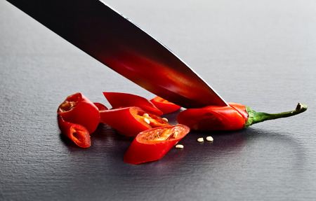 Knife and red chilli pepper on black tableの写真素材