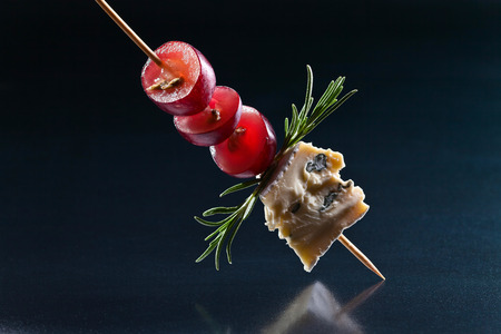 Blue cheese with grape and rosemary on a black backgroundの写真素材