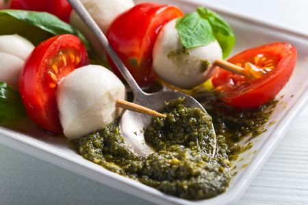 mozzarella with tomato , basil  and pesto sauce on a kitchen tableの写真素材