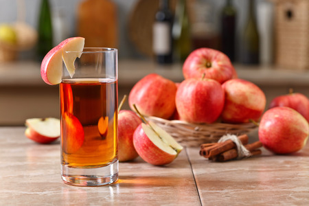 Glass of apple juice and ripe apples on a kitchen tableの写真素材