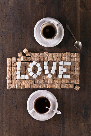 word love made of brown and white sugars and cups of coffeeの写真素材