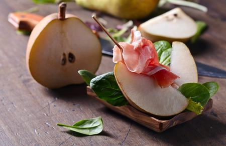 prosciutto with pear on a old wooden tableの写真素材