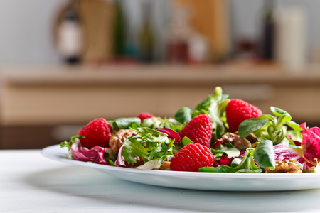 Green vegetarian salad with raspberry and nutsの写真素材