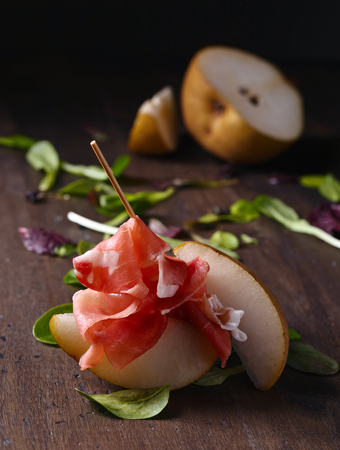 prosciutto with pear on a old wooden tableの写真素材