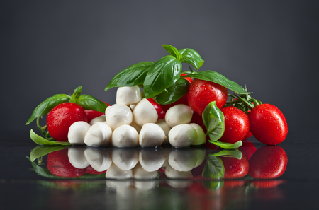 Mozzarella cheese with basil and tomatoes on black table.Healthy eating , Mediterranean cuisine .の写真素材