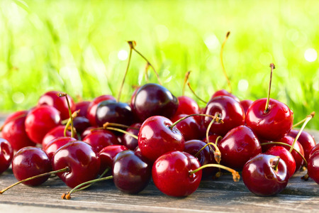 Ripe juicy cherries on wooden table in gardenの写真素材