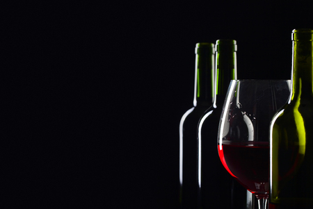 Bottles and glass of red wine on a black background . Selective focus .の写真素材
