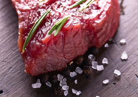 Beef steak with rosemary , salt and pepper on a old wooden table .の写真素材