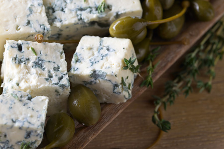 Blue cheese , capers and branches of thyme on a wooden table .の写真素材