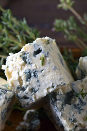 Blue cheese and branches of thyme on a wooden table .の写真素材