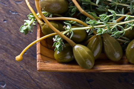 Canned capers and branches of thyme on a wooden table .Top view.の写真素材