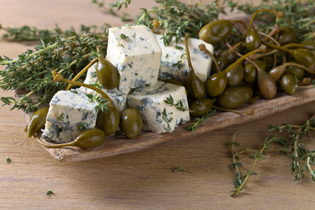 Blue cheese , capers and branches of thyme on a wooden table .の写真素材
