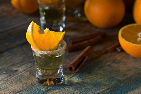 Gold tequila with orange and cinnamon on old wooden table .の写真素材