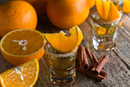 Gold tequila with orange and cinnamon on old wooden table .の写真素材