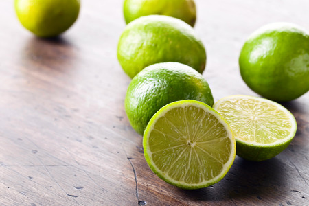 Group of whole and cut fresh limes on a old wooden table .の写真素材