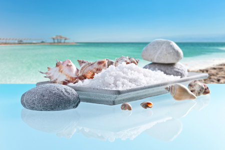 Sea salt on a glass table with stones and cockleshells on a background of the sea landscape.の写真素材
