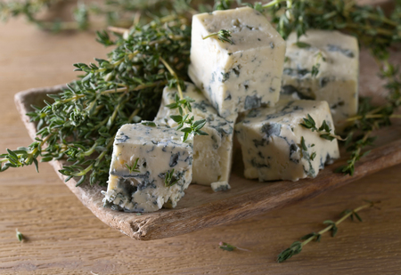 Blue cheese and branches of thyme on a wooden table .の写真素材