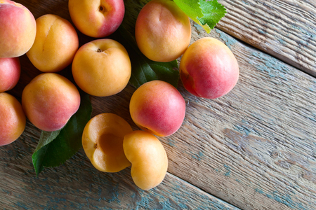 Juicy fresh apricots with leaves on old wooden table . Natural organic food . Top view.の写真素材