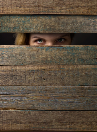 Woman watches through a hole in the wooden wall.Copy space .の写真素材