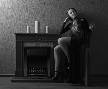 Beautiful blonde with perfect hair and professional  make-up in retro stile . Young beautiful woman with glass of brandy.の写真素材