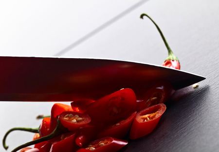 Knife and red chilli pepper on black tableの写真素材