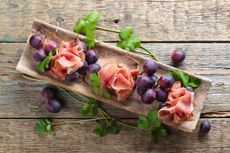 Jamon serrano with parsley and grape on a old wooden table . Healthy organic food .の写真素材