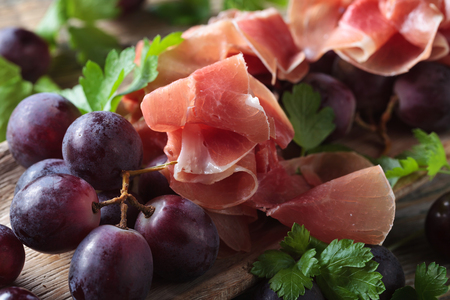Jamon serrano with parsley and grape on a old wooden table . Healthy organic food .の写真素材