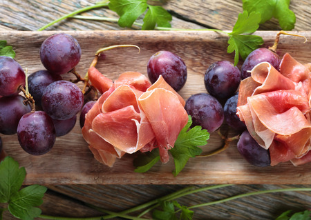 Jamon serrano with parsley and grape on a old wooden table . Healthy organic food .の写真素材